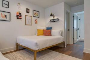 a bedroom with a white bed with colorful pillows at Taylor Haus II - Stylish Stay with Rooftop, Close to Fun in Nashville