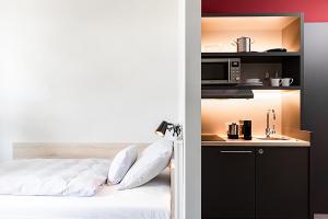 a bedroom with a bed and a kitchen with a microwave at HUB Apartments in Hamburg