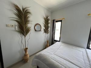 a bedroom with a bed and two plants in vases at Chandra's House in Denpasar