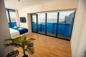 a bedroom with a bed and large glass windows at Panorama Sea View Orbi City Aparthotel Batumi Beach in Batumi