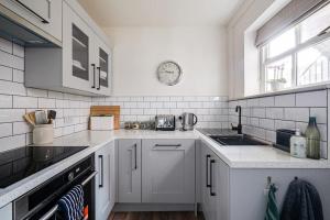 a kitchen with white appliances and a clock on the wall at Entire house, private parking, great views, dog friendly in Chester