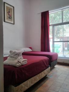 two beds in a room with a window at Hotel Minerva in Buenos Aires