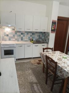 une cuisine avec des placards blancs et une table avec des chaises dans l'établissement SeaView Apartments Caprioli-Palinuro, à Palinuro