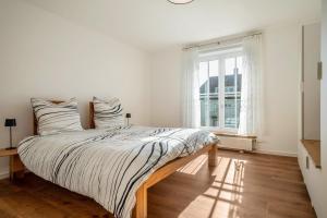 Un dormitorio blanco con una cama grande y una ventana en Windhager Seeblick, en Friedrichshafen