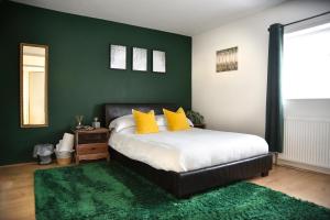 Hermitage, 3 Bed entire House in Loughborough في لاوْبورو: غرفة نوم بسرير ومخدات صفراء وجدار اخضر