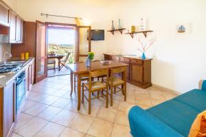 a kitchen and living room with a table and a couch at Sun and Sea LT - Piscina Condominiale - PMS CaseVacanze in Budoni