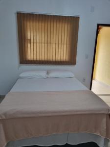a bed in a room with a window at Pousada Talismã in Barreirinhas