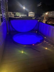 uma banheira de hidromassagem azul num pátio à noite em Tattershall Lakes Kingfisher Caravan 8 berth with Hot tub & WiFi em Tattershall