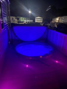 a hot tub with purple lights in a backyard at night at Tattershall Lakes Kingfisher Caravan 8 berth & Hot tub in Tattershall