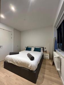 um quarto com uma grande cama branca com almofadas azuis em Stylish Brentford Riverside Penthouse em Brentford