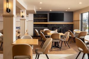 a waiting room with tables and chairs and a fireplace at Stonecroft Inn in Windsor