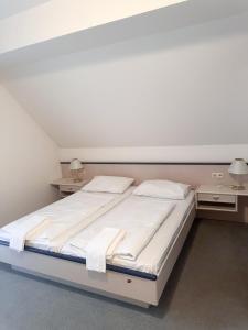 a white bed in a room with two night stands at Gasthof & Buschenschank Windisch in Gundersdorf