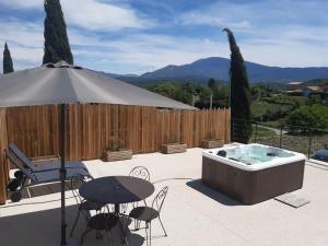 a patio with a hot tub and a table and chairs at Gîte du Colombier in Crestet