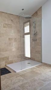 uma casa de banho com uma cabina de duche em vidro e uma janela. em Gîte du Colombier em Crestet