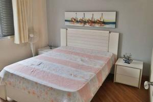 a bedroom with a large pink bed with two tables at Apartamento na aviação in Praia Grande