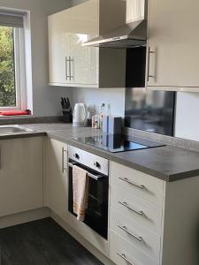 a kitchen with white cabinets and a stove top oven at Quiet Ground Floor apartment with parking in Morecambe