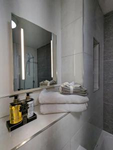 a bathroom with a mirror and towels on a shelf at NEW Lux 1 or 2 Bed Flats + Car Park + 5min Tube + Fast WiFi in London