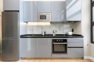 a kitchen with white cabinets and a stove top oven at Precioso dúplex en zona Vista Alegre en Madrid in Madrid