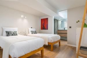two beds in a white room with a painting on the wall at Precioso dúplex en zona Vista Alegre en Madrid in Madrid