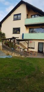 ein Haus mit einem Balkon und Bänken davor in der Unterkunft Ferienwohnung Karin in Eltmann