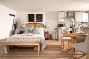 a bedroom with a bed and a table and a kitchen at Meadow - Woodland Cottage with Private Hot Tub in Blandford Forum