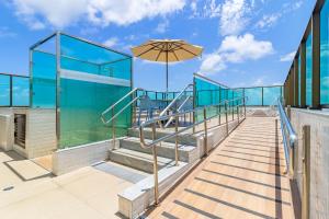 un edificio de cristal con escaleras y sombrilla en Beach Class #3506 - Suíte Confortável by Carpediem, en Recife