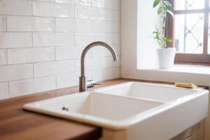 ein weißes Waschbecken in einer Küche mit Fenster in der Unterkunft Maison au cœur de Saint-Émilion in Saint-Christophe-des-Bardes