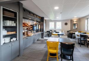 a dining room with tables and yellow chairs at B&B HOTEL Lille Lezennes Stade Pierre Mauroy in Lezennes