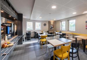 a dining room with tables and yellow chairs at B&B HOTEL Lille Lezennes Stade Pierre Mauroy in Lezennes