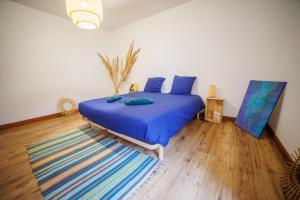 Schlafzimmer mit einem Bett mit blauen Kissen und einem Teppich in der Unterkunft Maison au cœur de Saint-Émilion in Saint-Christophe-des-Bardes