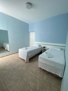 - 2 lits dans une chambre avec un mur bleu dans l'établissement POUSADA OASIS DE MINAS, à Carmo do Rio Claro