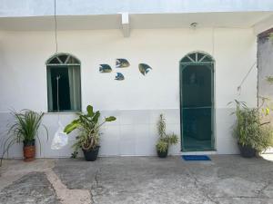 瓜賓的住宿－Casa do Sossego，白色的墙壁,有绿门和盆栽植物