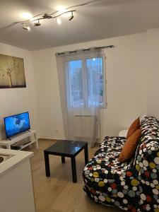 una sala de estar con un sofá y una mesa en Appartement lumineux près métro, en Saint-Denis