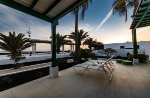 eine Terrasse mit einem Stuhl, einem Tisch und Palmen in der Unterkunft Luxury Villa Sea Front -La Orilla in Playa Honda