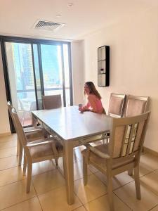 a woman sitting at a dining room table with chairs at Arabian Nights Beach Hostel in Dubai