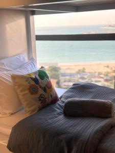 Cama con almohada y vistas al océano en Arabian Nights Beach Hostel, en Dubái