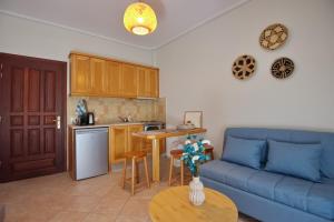a living room with a blue couch and a kitchen at Pefka Apartments in Votsi