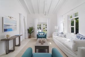 a white living room with a white couch and blue chairs at Coral House 3 bedroom home in Saint Peter