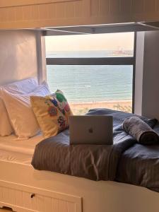 ドバイにあるArabian Nights Beach Hostelのビーチの景色を望むベッド(ノートパソコン付)