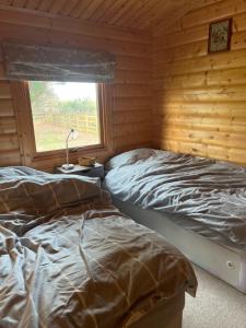 2 camas en una cabaña de madera con ventana en Holme Woodmans Lodge en Holme