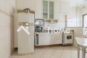 uma cozinha branca com um frigorífico e uma mesa em Apartamento a 450m da Praia em Praia Grande na Praia Grande