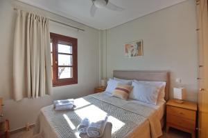 a bedroom with a bed with white sheets and a window at Pefka Apartments in Votsi +28 photos