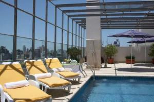 uma piscina com cadeiras e um guarda-sol num edifício em Ariston Hotel em Rosário