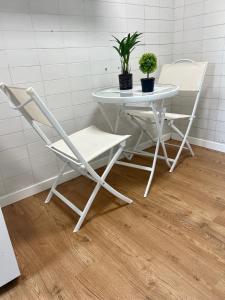 Habitación en Madrid في مدريد: طاولة بيضاء وكراسي عليها نباتات