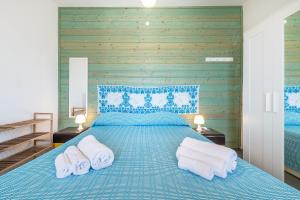 a bedroom with a blue bed with towels on it at Villa Celeste in Cagliari