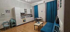 Apartament On Aghmashenebeli 26 في تبليسي: غرفة معيشة مع أريكة زرقاء ومطبخ