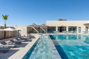 a swimming pool with chairs and a building at Kenzi Rissani in Er Rachidia