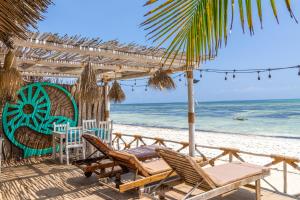 ein Strand mit Stühlen und einem Sonnenschirm und das Meer in der Unterkunft Pili Pili Sunrise in Jambiani