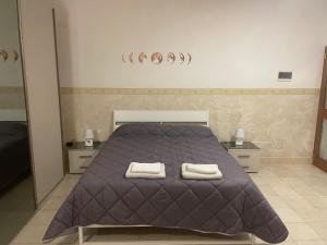 een slaapkamer met een paars bed en 2 handdoeken bij La Dependance in Barletta