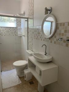 La salle de bains est pourvue d'un lavabo, de toilettes et d'un miroir. dans l'établissement POUSADA OASIS DE MINAS, à Carmo do Rio Claro